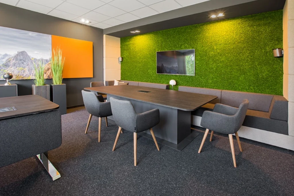Innovativer Konferenzraum mit Mooswand und modernen Büromöbeln – kreative Arbeitsumgebung.